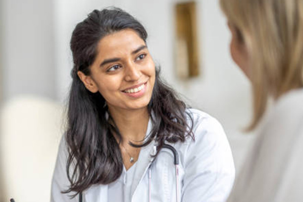 Healthcare professional with stethoscope and warm smile converses with patient at Nelson Vein.