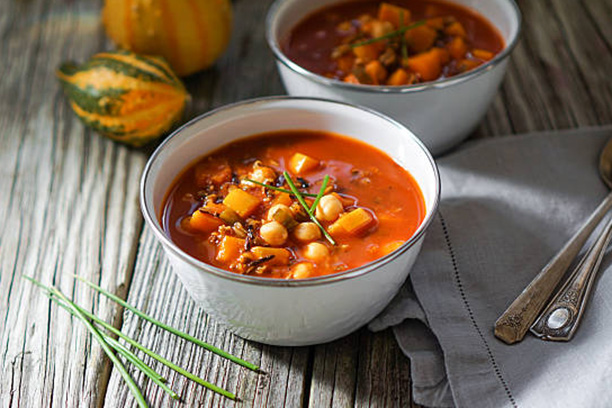 Vegetarian tasty spicy chili chick pea pumpkin wild rice soup pozole stew bowl on a wooden background.