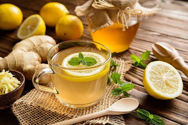 Cup of ginger root tea with lemon, honey and mint on a wooden background