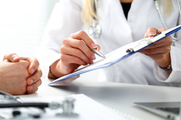 Doctor in white coat reviews medical report and patient forms with patient at Nelson Vein, Cleveland, Ohio - Treatment for Varicose Veins and Spider Veins