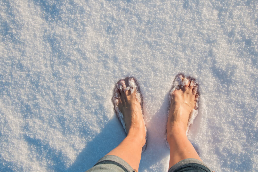 A man standing barefoot in the snow.