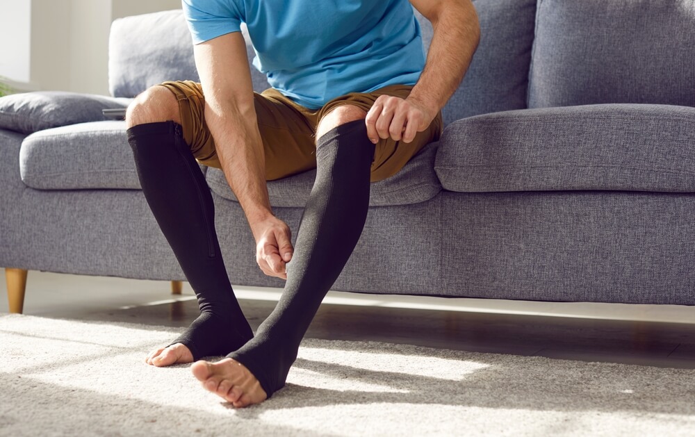 A man putting on knee-high compression socks.